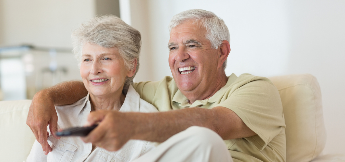 Elderly people sitting on a couch, smiling