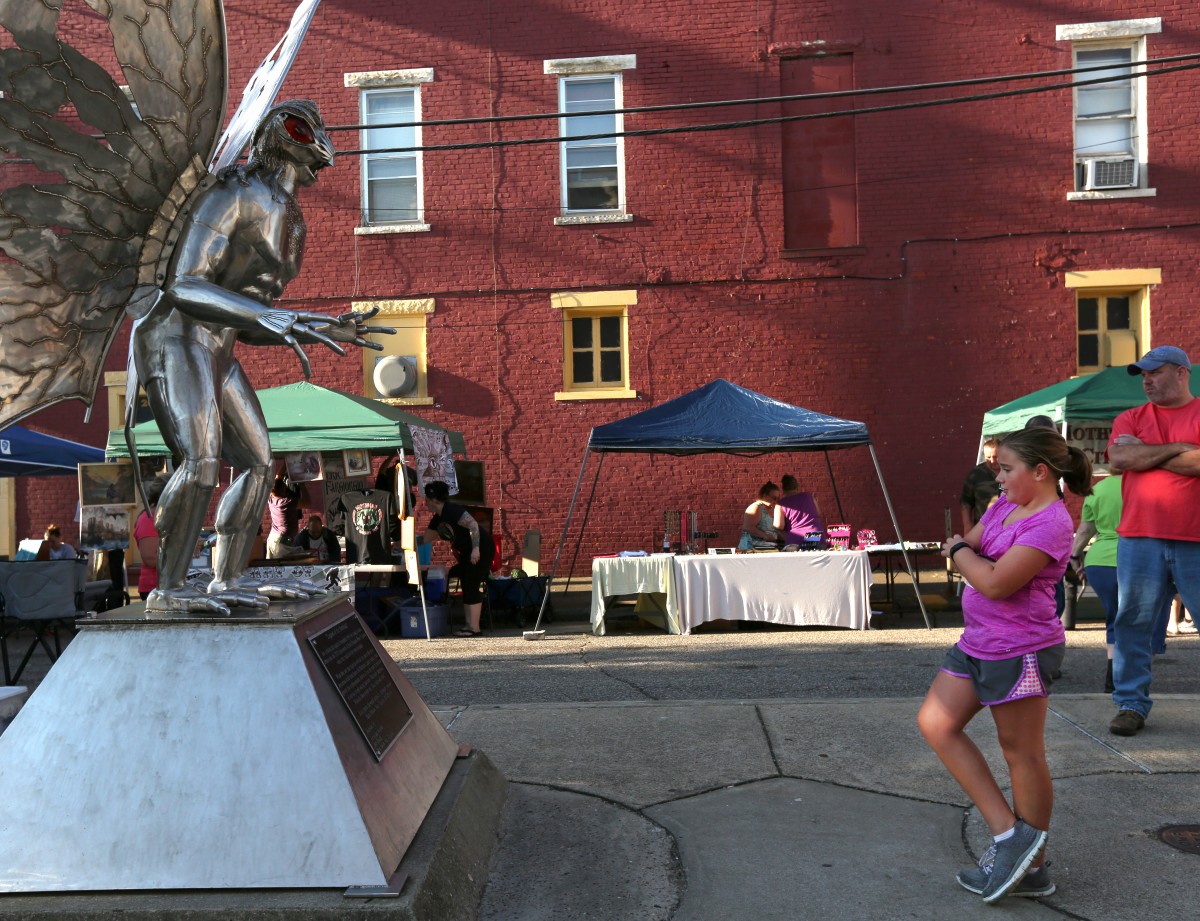 After running the Mothman 5K Saturday morning, Lily Schneider reads a plaque explaining the significance of the Mothman on a statue in downtown Point Pleasant, W. Va. (Jennifer Coombes/WOUB)