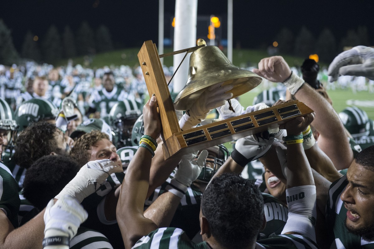 The Ohio Bobcats celebrate their 21-10 win against Marshall with the Battle of the Bell trophy.