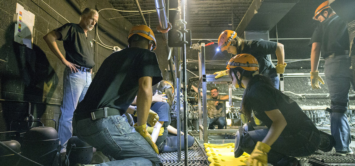 Jeff Russell (far left), director of the SHAPe Clinic, and Lowell Jacobs (background center), master electrician with School of Theater, guide students through emergency response procedures in the Forum Theater's lighting grid. (Matthew Forsythe)