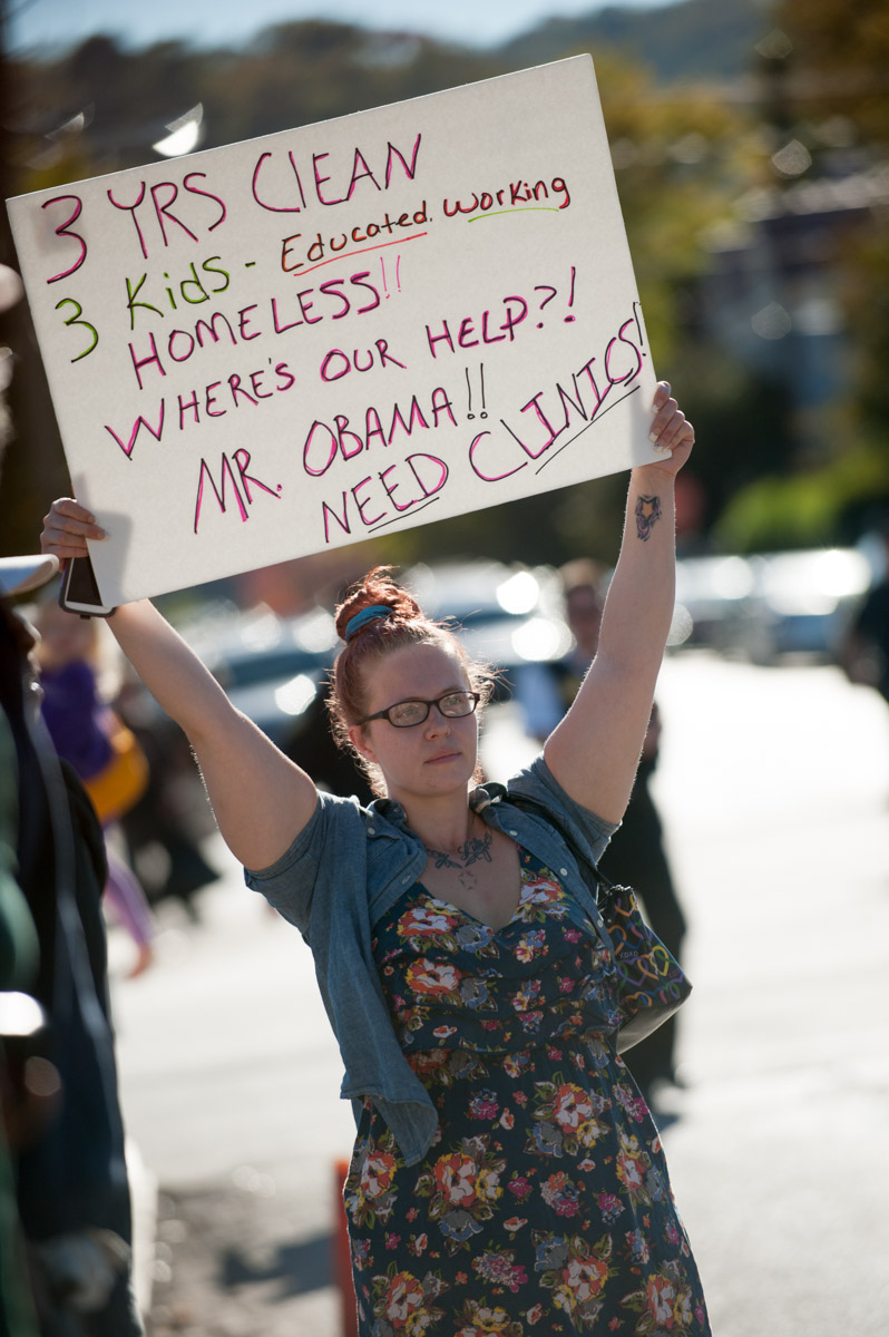 Jessica Short holds up a sign as she waits for the president's motorcade to pass by. Short resides at Sojourner's Homeless Shelter in Charleston. (Yi-Ke Peng/WOUB)