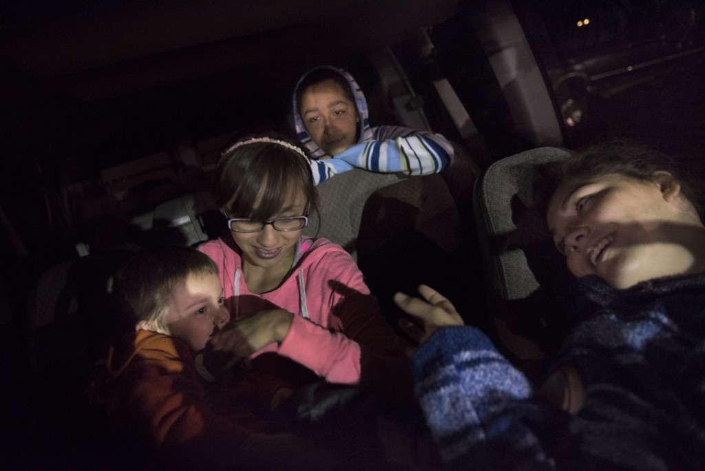From left to right, Levi, Olivia, May, and Nina hang out in their family's 15-person van between their brother Gabe's races at his motocross competition.