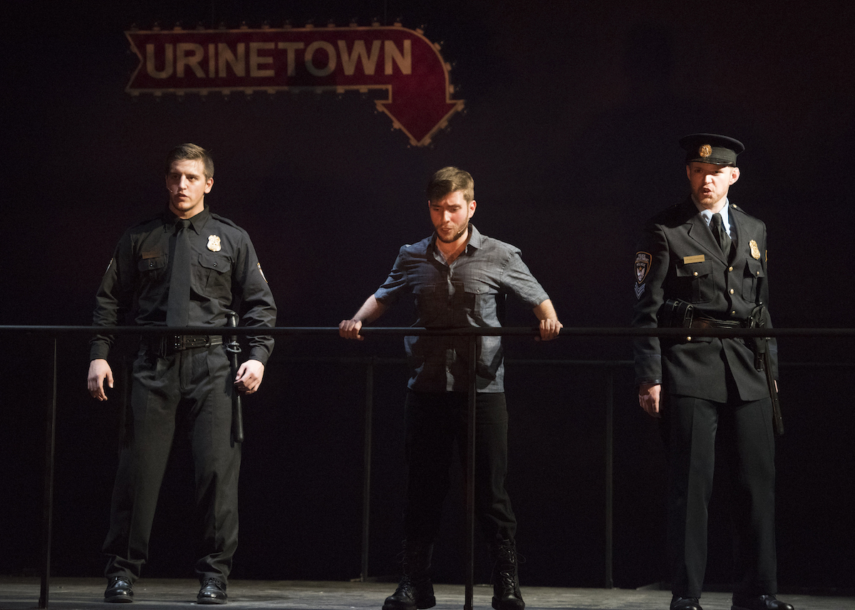 Bobby Strong (center) learns what Urinetown really is and is sent to his death by Officer Lockstock (right) and Officer Barrel (left). 