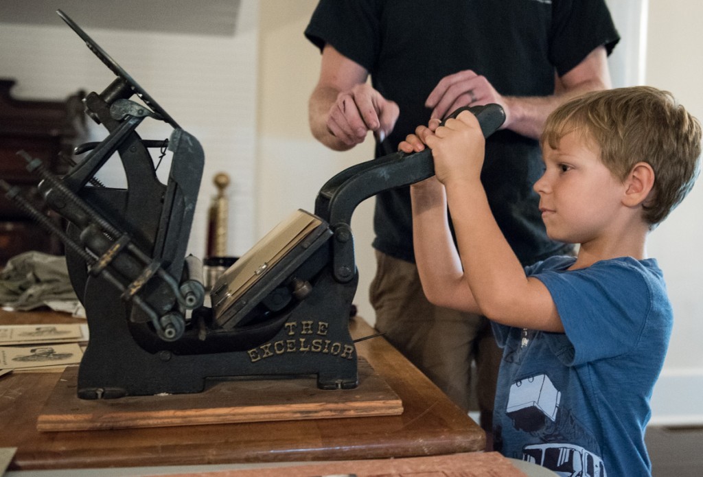 Henry,5, from Athens, Ohio, learns how to use an old fashioned ink press at Stuart’s Opera House. (Robert McGraw/WOUB)