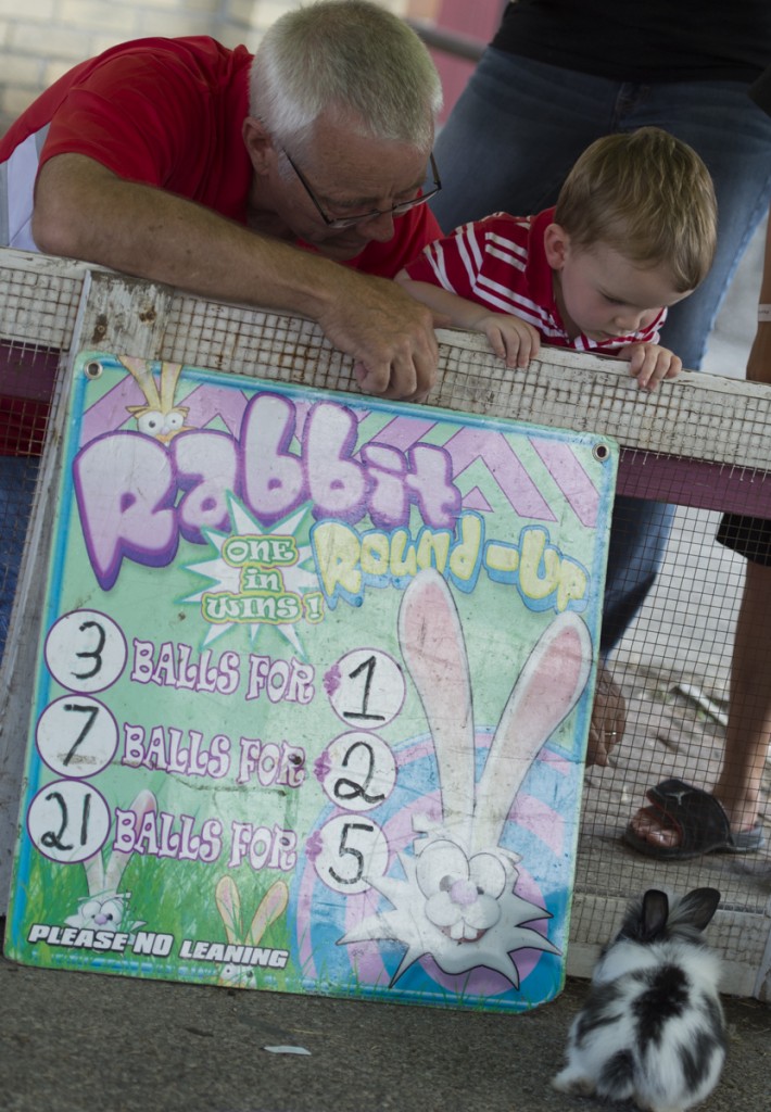 David Porter I (left) and David Porter III, 2, (right) from Wheelersburg, Ohio,  watch the bunnies during one of the carnival games at the 2016 Wellston Coal Festival. (Robert McGraw/WOUB)