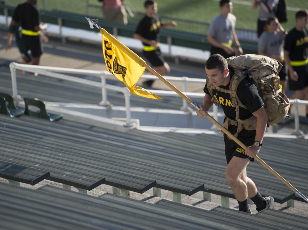 An Army ROTC cadet runs the steps of Peden during the 2nd annual 9/11 Challenge holding the ROTC flag and wearing his camouflage back pack.(Robert McGraw/WOUB)