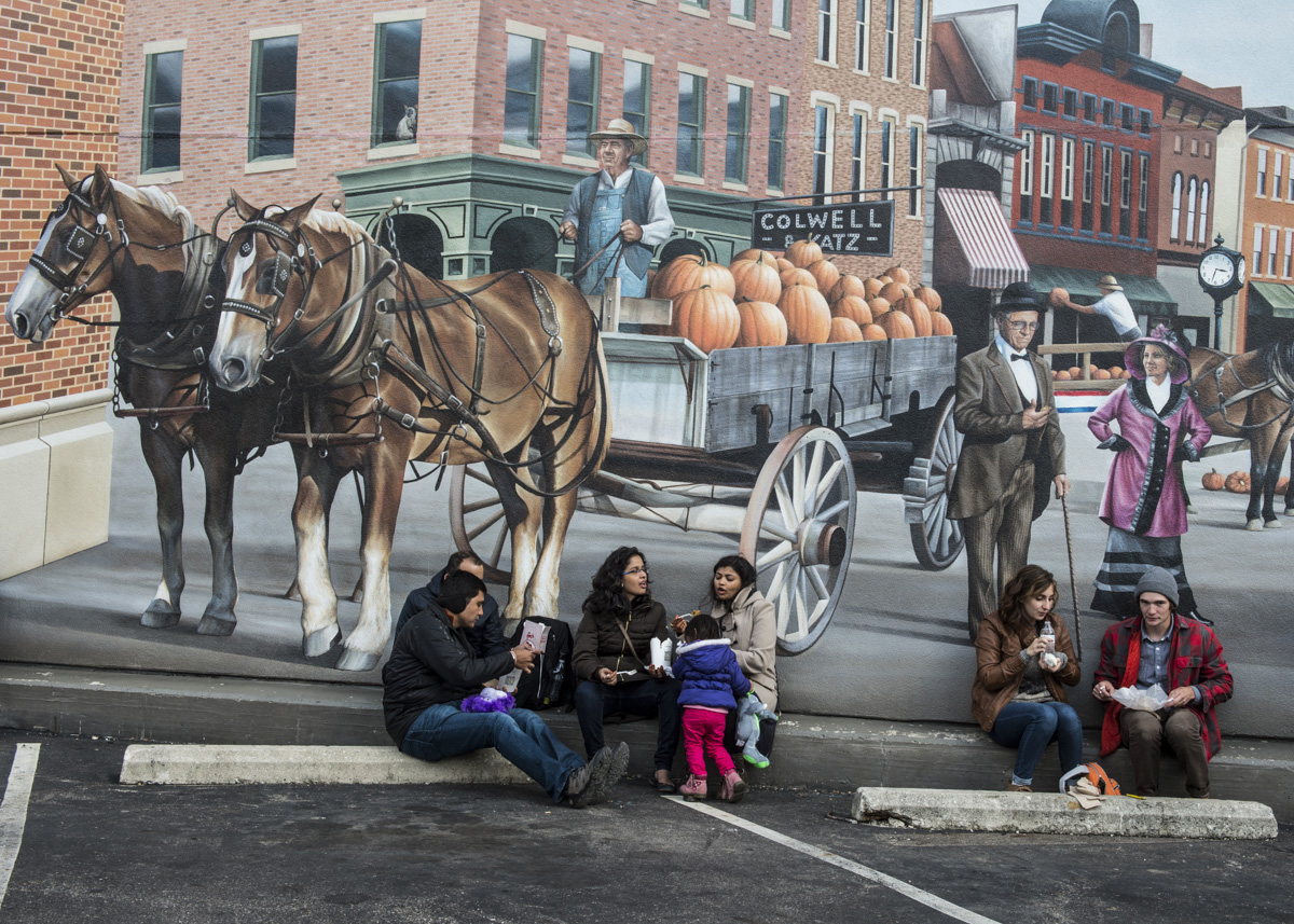 People from all over the world come and sit in front of the Cornerstone Mural and eat various types of food at the Circleville Pumpkin Show on October 22, 2016. (Robert McGraw/WOUB)