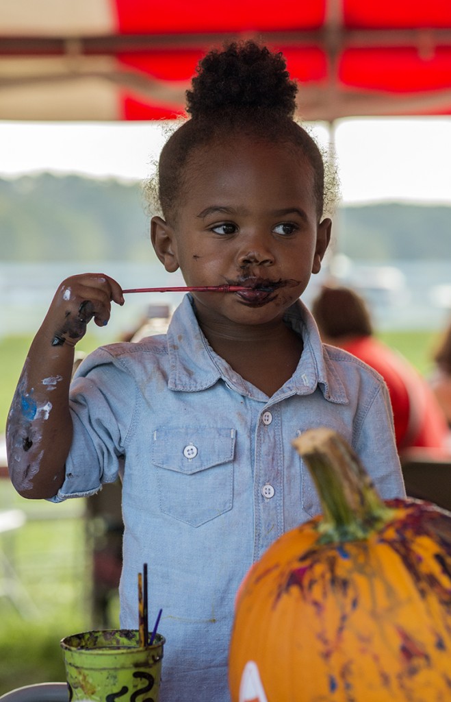 Lyric Powell, 2, paints her lips with black paint after finishing painting her pumpkin in the Make and Take tent during the 46th annual Bob Evans Farm Festival on Saturday, Oct., 15, 2016 in Rio Grande, Ohio. (Kelsey Brunner/WOUB)