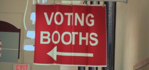 A red sign with white lettering that reads voting booths