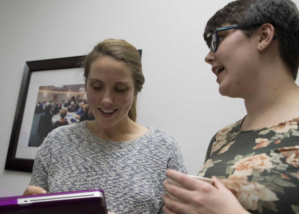 Rural Action Social Media intern Kaitlin Owens, right, gets Katelyn Eilbeck, left, information and picture for a New Year’s resolution social media campaign #newyearnewaction.  (Robert McGraw/WOUB)