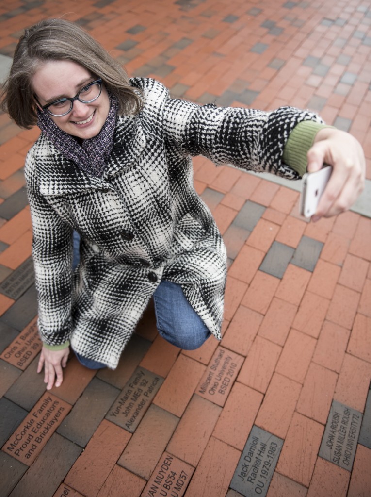 Sarah McCorkle, a graduate of The Patton College of Education, takes a selfie outside of McCracken Hall with the commemorative brick with her family name on January 27, 2017. (Robert McGraw/WOUB)