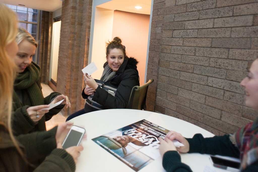 McKennah Robinson shows the name of her randomly assigned product to fellow Ohio University students Leah Keiter (left), Cara Hansen, and Danielle McCarthy on Friday, 27 January 2017 in Athens, Ohio. The drawing of index cards marks the beginning of Ad Club's annual Ad Bowl, a competition requiring contestants to write and film an advertisement on their cell phones in a period of 24 hours. (WOUB / Drake S. Withers)