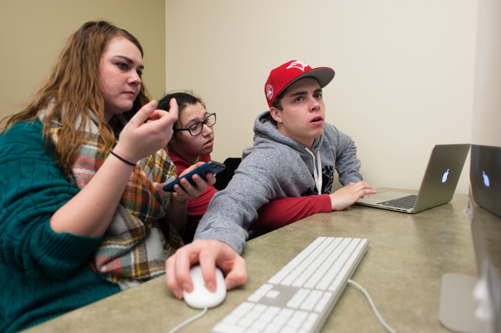 Arms tangle as Gabby Hollowell (left), Sarah Abrams and Jackson Baehr discuss potential editing ideas during Ad Club's annual Ad Bowl on Saturday, 28 January 2017 in Athens, Ohio. (WOUB/Drake S. Withers)