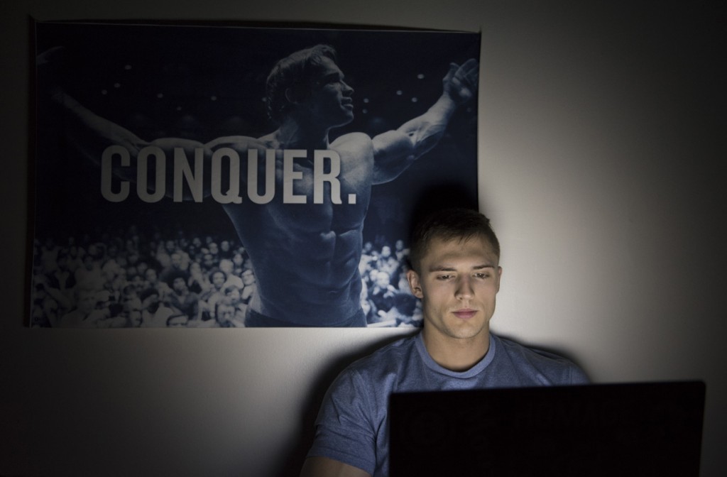 Nick, a senior mechanical engineering student at Ohio State University, makes daily adjustments to his competition diet before going to bed at 8 pm. Behind him is one of several inspirational posters that he has placed in his room as he prepares for the upcoming competition at the Arnold Sports Festival. (Robert McGraw/WOUB)