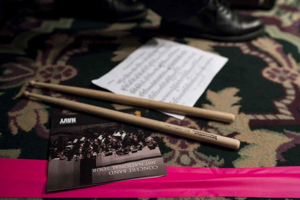 A sheet of music, drum sticks, and a U.S. Navy Band program lay on the ground next to the feet of a high school band member that was featured in the April 6 performance of the U.S. Navy Band. (Michael Swensen/WOUB)