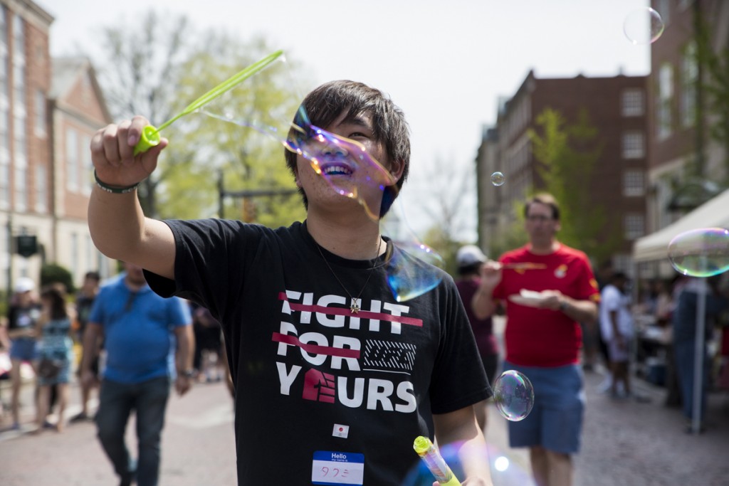 Takumi Koide, an undergraduate student from Japan, blows bubbles on the International Week Street Fair on the Court Street in Athens, Ohio, on April. 15, 2017. (Wangyuxuan Xu/WOUB)