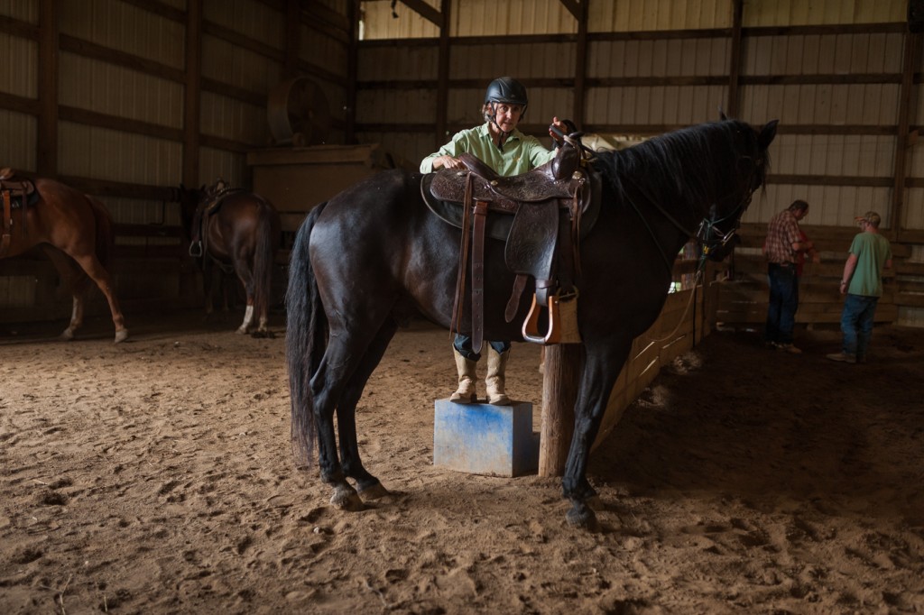 A cowgirl participating in Smoke Rise Ranch's "Cowgirl Bootcamp" prepares to mount her horse before learning how to heard cattle. (Michael Swensen/WOUB)