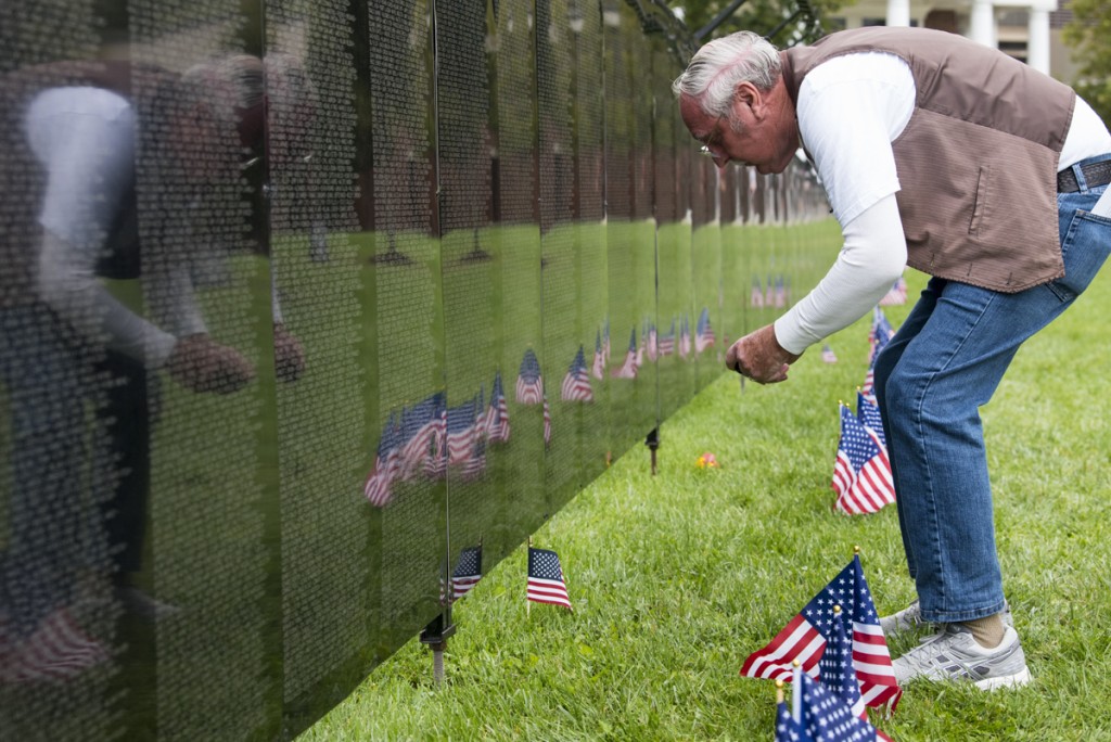 Glenn Tenney leans over to make a photo of a name on the Vietnam Wall mock-up displayed in bicentennial park in Athens, Ohio on September 15, 2017.  (Robert Green/WOUB)