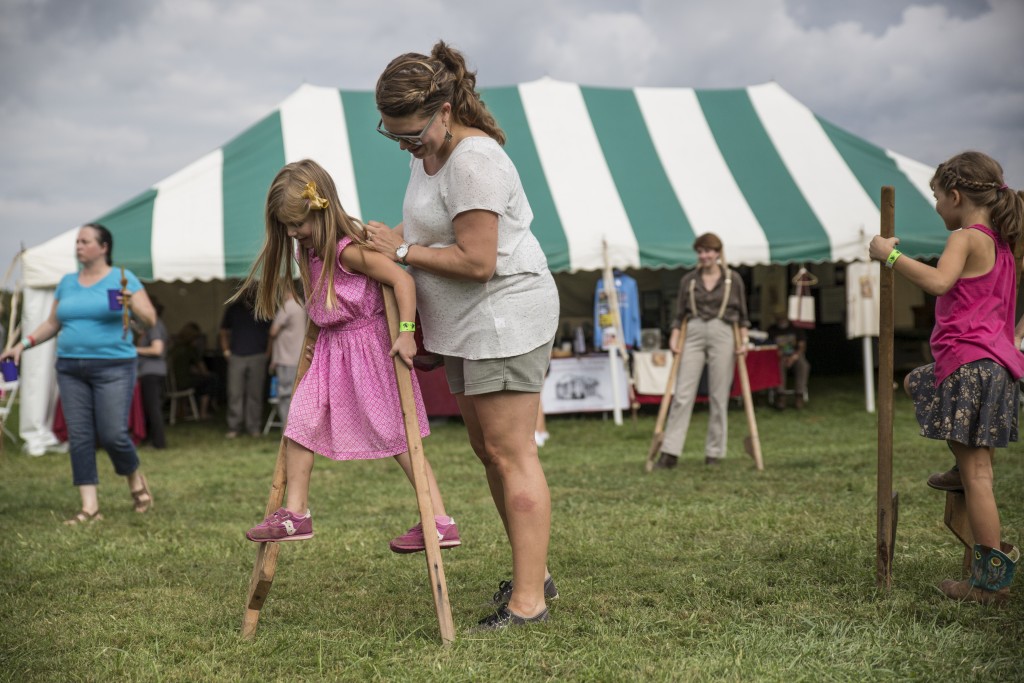 Amanda Petroff teaches her 5-year-old daughter, Scarlet Petroff, to play Walking-on-Stilts in Paw Paw Festival in Albany, ohio on Sep.16, 2017.(Wangyuxuan Xu/WOUB)