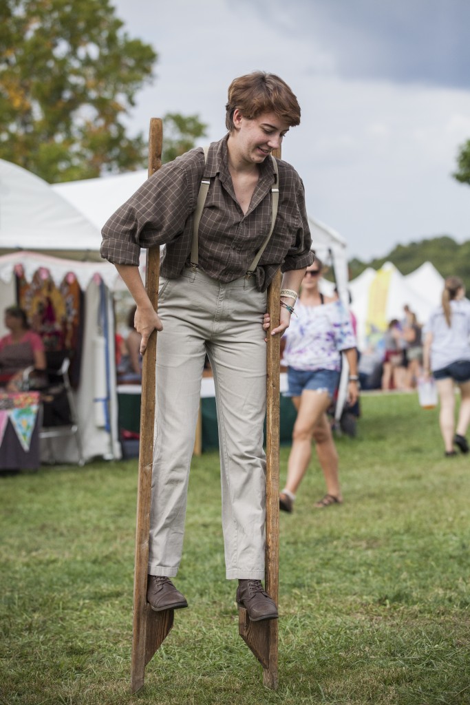 Sarah Haney,  a student of Natual and Historical Interupting game program in Hocking College, shows people how to play a traditional game- walking on stilts in Paw Paw festival in Albany, Ohio on Sep. 16, 2017. (Wangyuxuan Xu/WOUB)