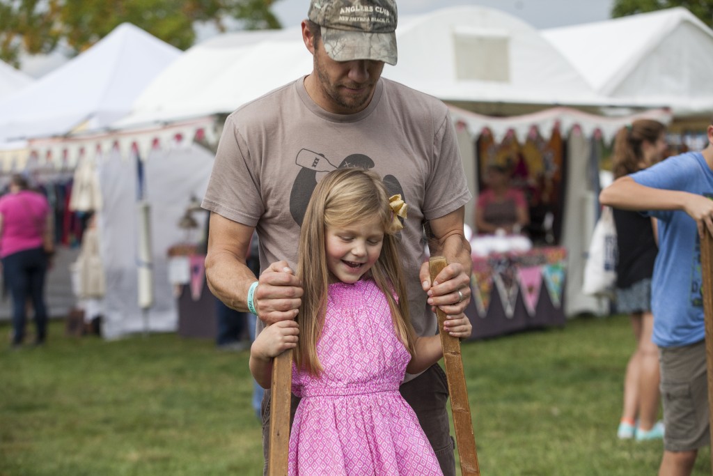 Scott Petroff teaches his 5-year-old daughter, Scarlet Petroff, to play Walking-on-Stilts at the Paw Paw Festival in Albany, Ohio on Sep.16, 2017. (Wangyuxuan Xu/WOUB)