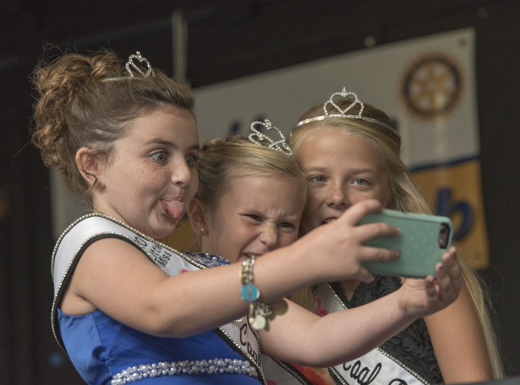 (From left to right) Shelby Smith, Ella Hitchinson, and Lindsey McCormick, take a selfie together at the Little Miss Coal Festival Queen Contest. (Austin Janning/WOUB)