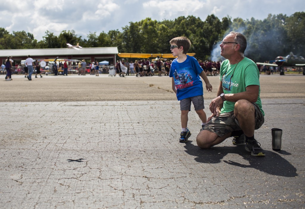Steve Draudt teaches his grandson, Gavin Hunter, 4, how to properly fly a small, wooden airplane on the tarmac of the Vinton County Airport during the Air Show on Sunday, September 17, 2017. (Erin Clark/WOUB)