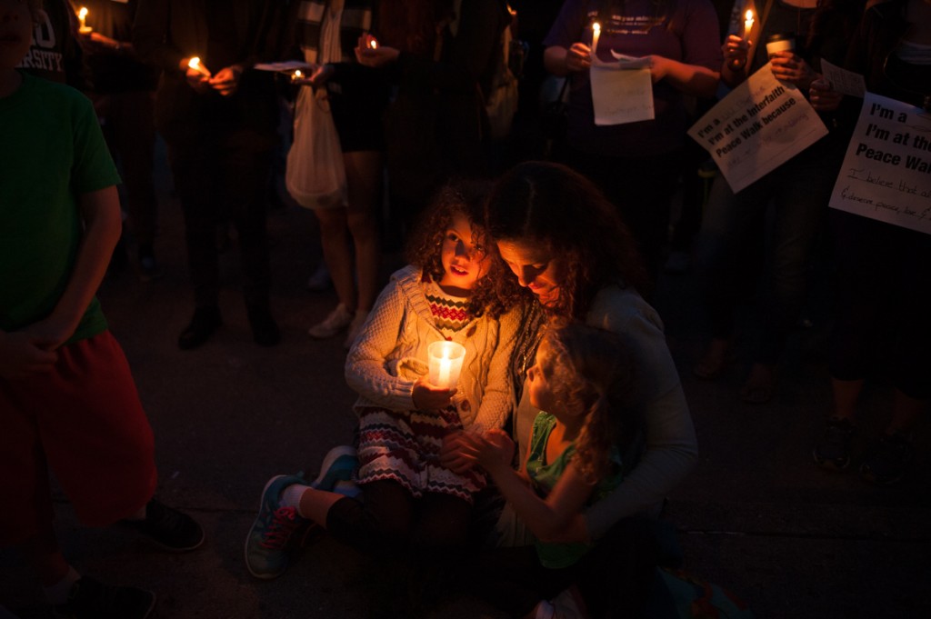 Rachel Siegel holds her daughters, Talia and Evelyn Siegel, as they sing hymns during the candlelight vigil at the close of the Interfaith Peace Walk on Monday, Sept. 11, 2017. (Drake S. Withers / WOUB)