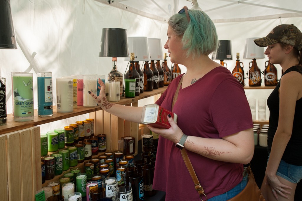 Hannah McAninch (left) and Mary Sapp, from Columbus Ohio, look at homemade candles in recycled alcohol bottles in Steve Hoke's booth at the Backwoods Fest in Thornville, Ohio.