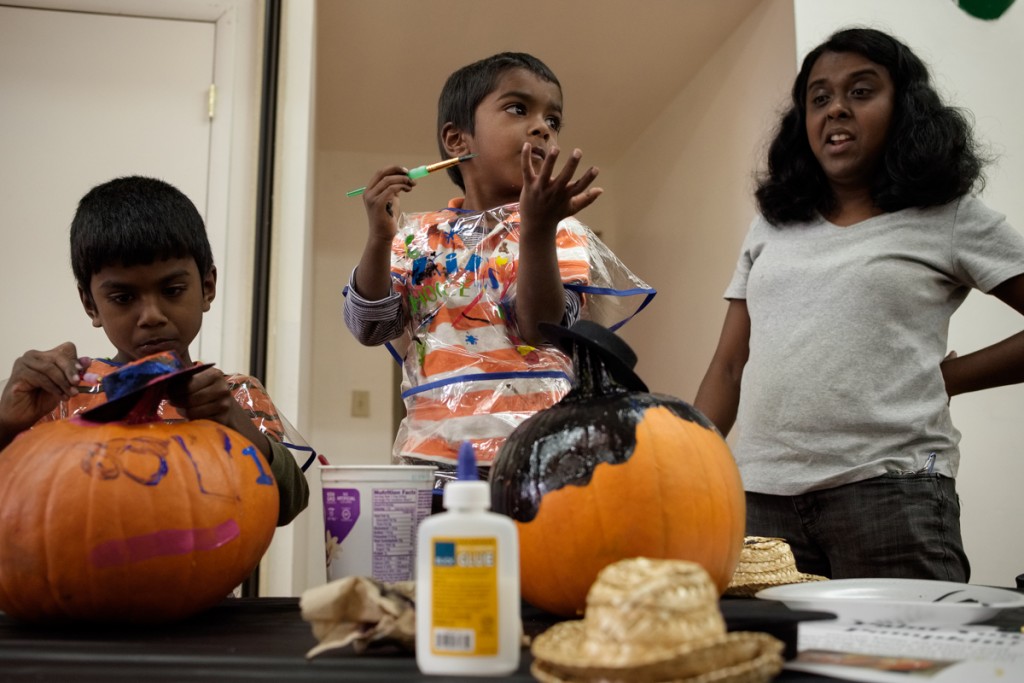 Caleb Briju, 3, paints a pumpkin with his brother, Rufus Briju, 7 (left), and his mother, Betsy Briju, at the Dairy Barn Arts Center in Athens, Ohio, on Saturday, October 21, 2017. (Drake Withers / WOUB)