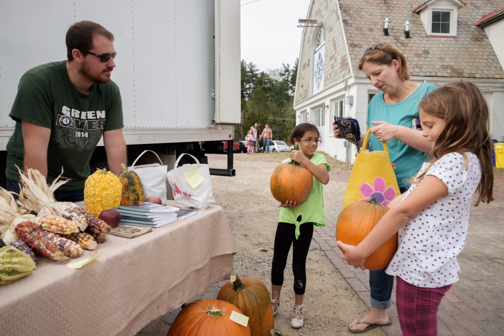Luke Welch sells pumpkins to Aubrey Krummert, her daughter Clara Arauz, 8 (left), and Clara's friend Summer Forster, 8 (right) during the annual Pumpkin Fest at the Dairy Barn Arts Center in Athens, Ohio, on Saturday, Oct. 21, 2017. (Drake Withers / WOUB)