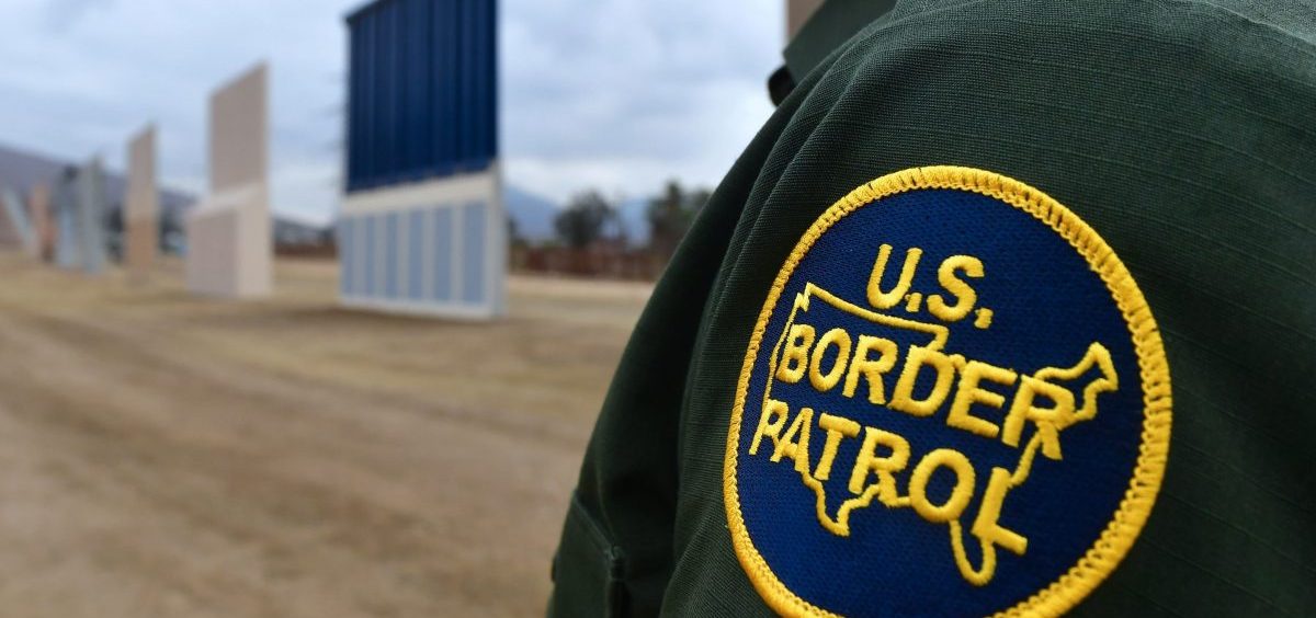 A U.S. Border Patrol officer stands near prototypes of President Trump's proposed border wall in San Diego.