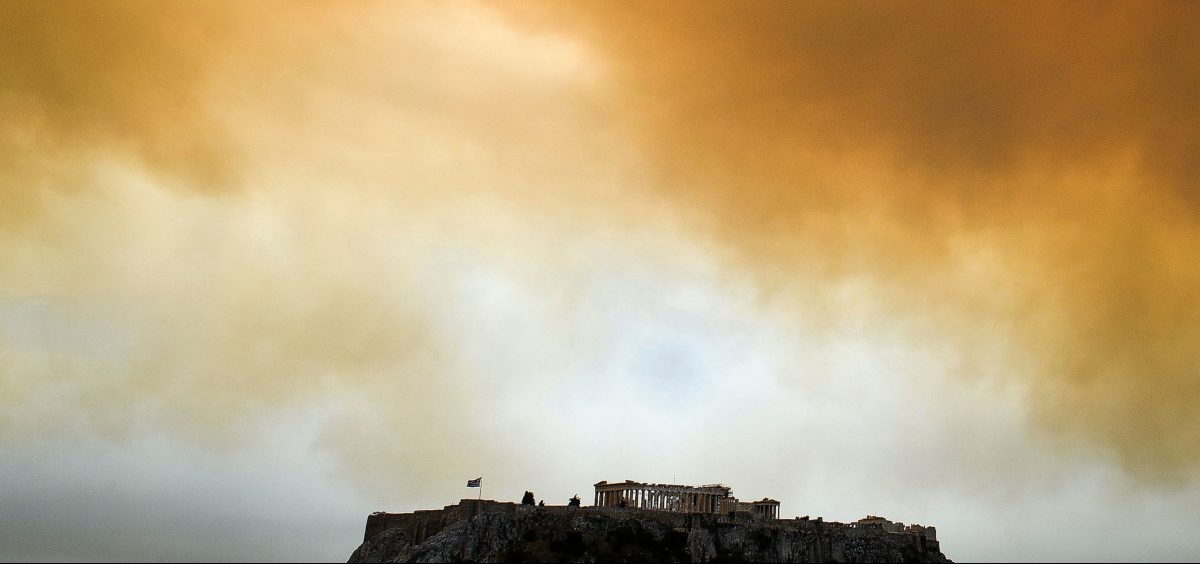 A picture taken on July 23, 2018 shows the Parthenon temple on the Acropolis hill in Athens as smoke billows in background during a wildfire in Kineta, near Athens.