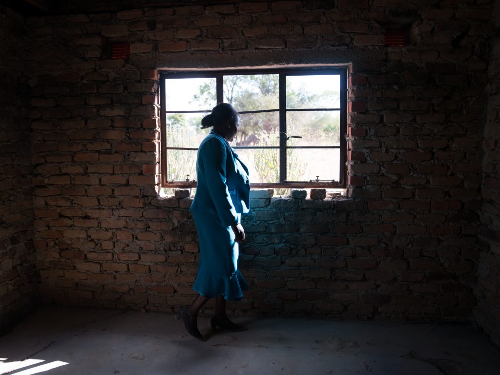 Florence Machinga, a candidate for the opposition MDC party, looks out the window of her house, which was burned down 10  years ago by an angry mob. The incident was one in a wave of violence carried out against MDC supporters in 2008. Machinga is still slowly rebuilding the home.