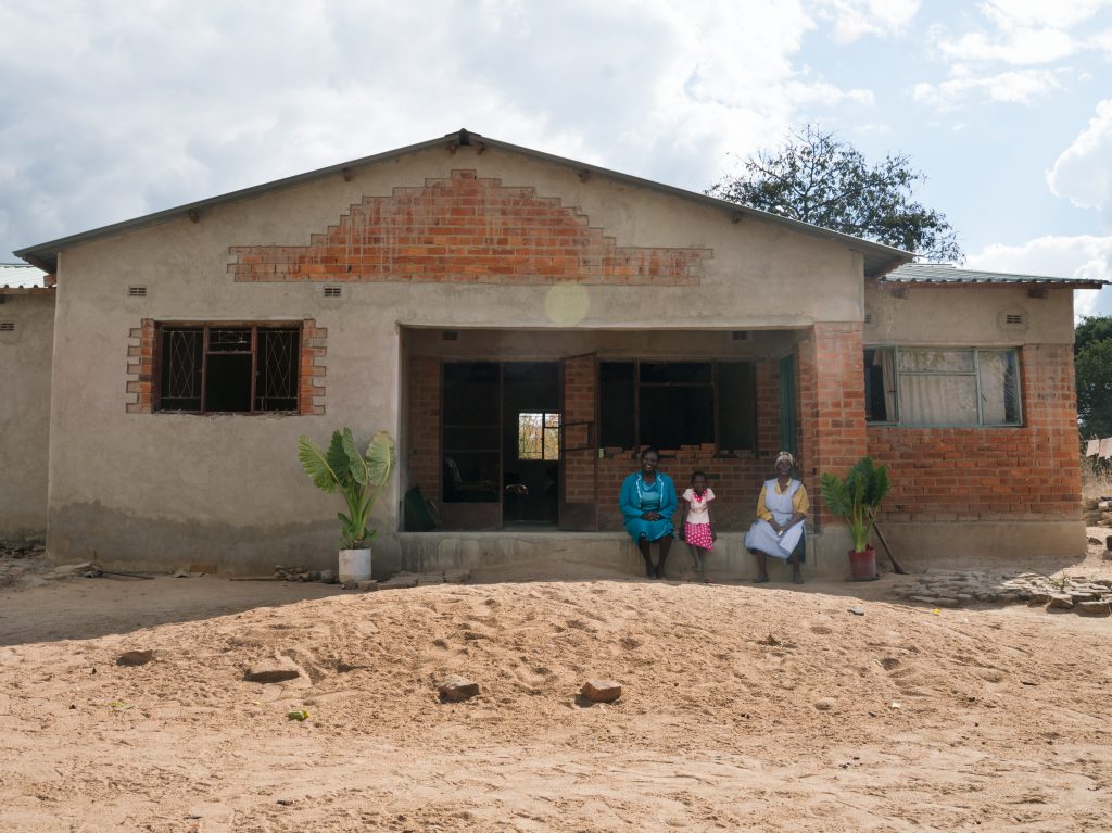 Florence Machinga with her daughter Hazel and mother Rosemary at the home they are slowly rebuilding after it was destroyed in 2008.