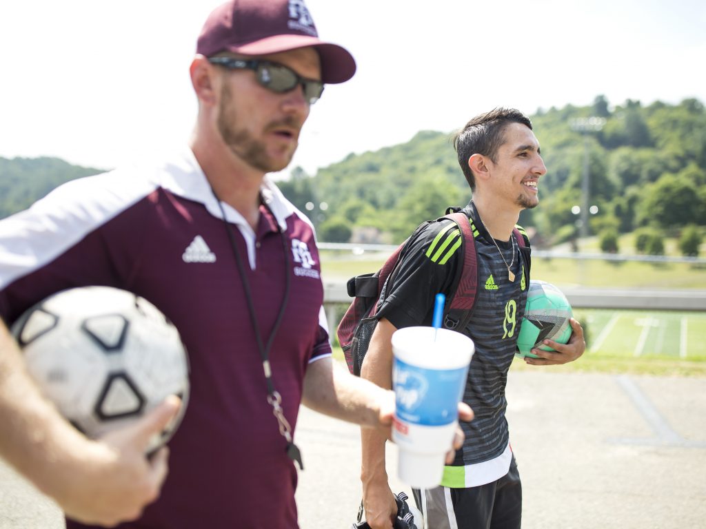 Ricardo Osuna, right, who graduated from high school this spring, and head soccer coach Troy Barkley, left, leave the Galax High School field. Osuna helped to lead the school's soccer team to the state championship title the past two years. Barkley credits the sheer love of soccer that his Hispanic players have as a contributing factor to the team's success.
