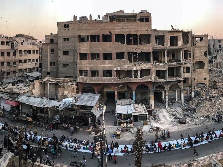 During a lull in the bombings, Syrians in the city of Douma gather for the evening meal at the end of a Ramadan fast.