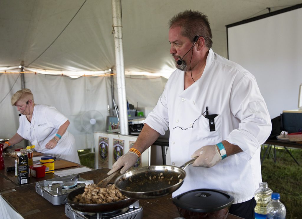 Dave Rudie, a local cook from Marietta, Ohio, shows the audience how to use paw paw to cook buttered milk chicken with his co-worker Dagmar Kupsche at the Ohio Paw Paw Festival in Albany, Ohio on Sept 15, 2018. (Yukai Peng/WOUB)