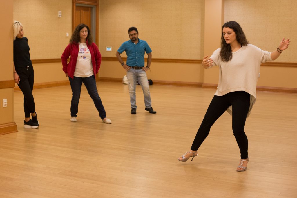 Tango Club instructor Maria Casa demonstrates how the follower’s body should move while doing the back ocho, as Tanya Tytko (from left), Tracy Shust, and Dibya Ghosh watch her movements in Baker Student Center at Ohio University on Thursday, October 11, 2018. (Hannah Schroeder/ WOUB)