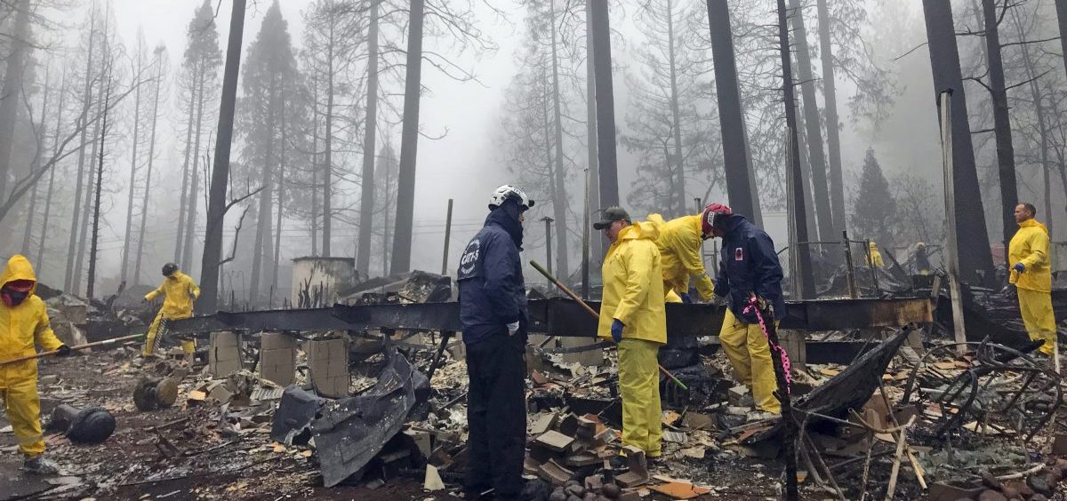 Volunteers search a mobile home park in Paradise, Calif. Government scientists predict wildfires like the one that struck this community will contribute to billions in loses for the U.S. economy.