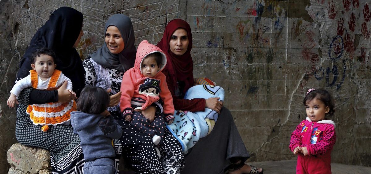 Syrian refugee women hold their children in a refugee compound in the southern port city of Sidon, Lebanon.