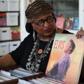 woman holding up Elvis album in record store