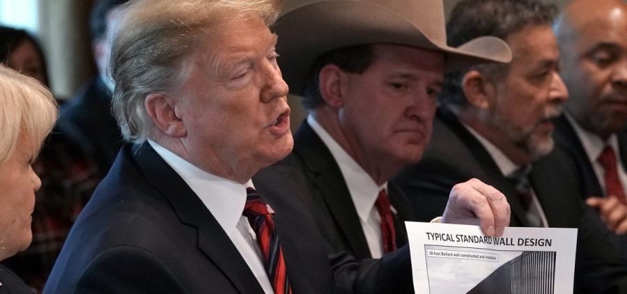 President Trump holds a picture labeled "typical standard wall design" as he hosts a roundtable discussion on border security in the Cabinet Room of the White House on Friday.