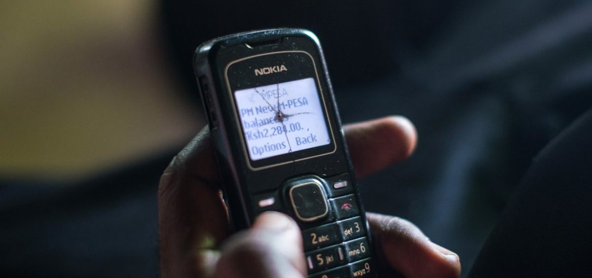 A poor resident of a village in Kenya checks his phone to confirm that a cash transfer has been made.