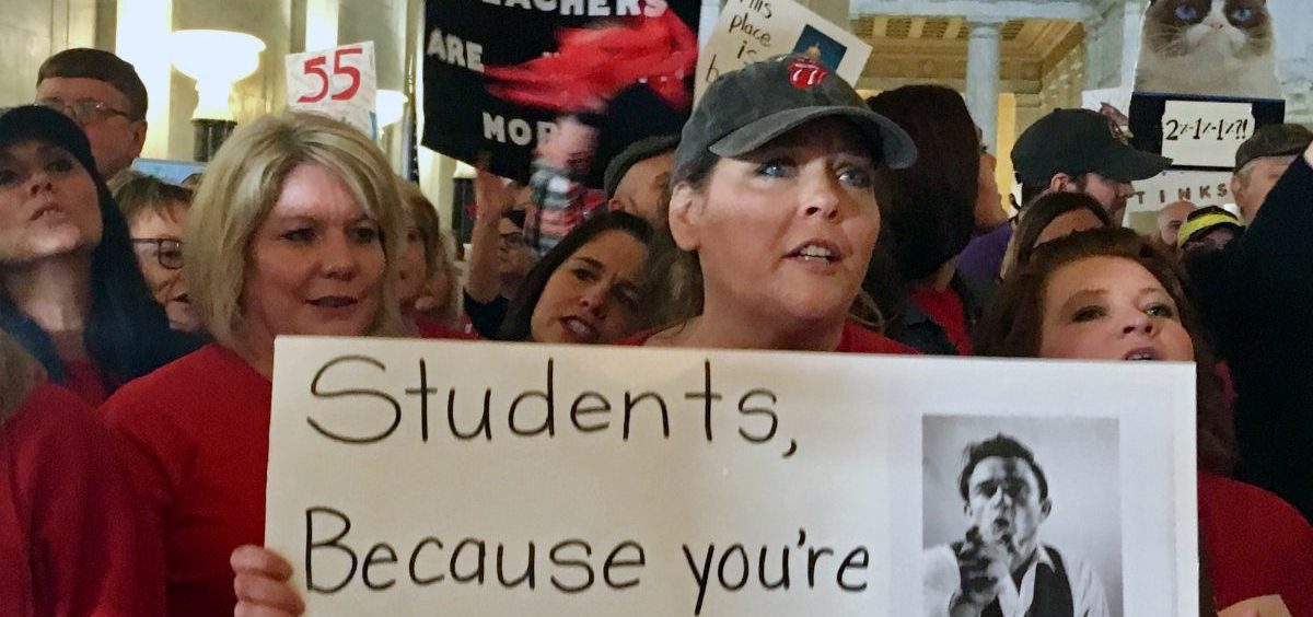 In a 2018 photo, teacher Jennifer Hanner holds a sign outside the state Senate chambers at the Capitol in Charleston, W.Va.