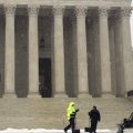 Crews remove early morning snow during a winter storm at the Supreme Court on Wednesday. It's not unusual for the high court to be open when the rest of Washington is closed.