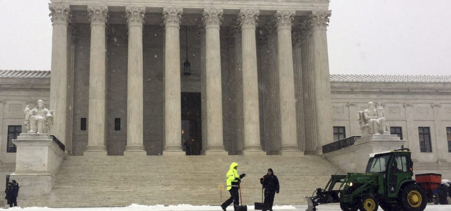 Crews remove early morning snow during a winter storm at the Supreme Court on Wednesday. It's not unusual for the high court to be open when the rest of Washington is closed.