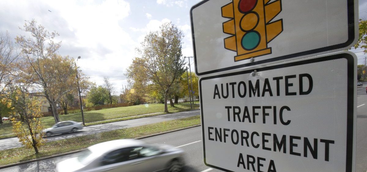 Motorists drive past a sign warning of upcoming traffic cameras in Cleveland.
