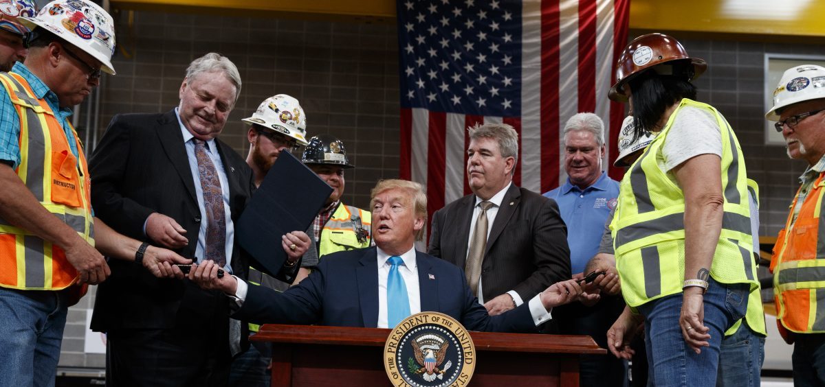 President Trump hands out pens after signing an executive order aimed at making it easier for companies to pursue oil and gas pipeline projects. The president addressed an audience at the International Union of Operating Engineers International Training and Education Center in Texas.