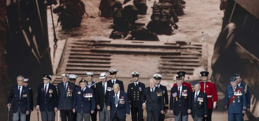 Veterans stand in front of a 1944 image of their comrades wading onto the beaches of France during D-Day commemorations in Portsmouth, England. Leaders of 16 countries involved in World War II joined Queen Elizabeth II at the ceremony on Wednesday.